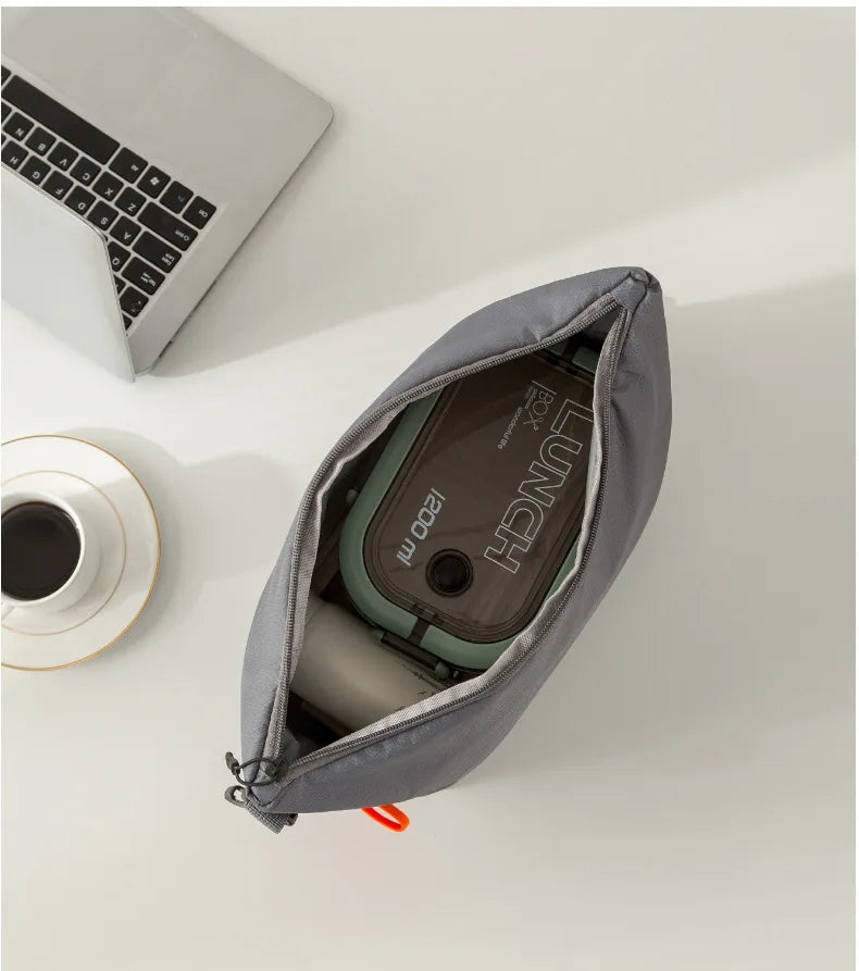 Gray pouch with a device inside on a white surface next to a laptop and coffee cup.