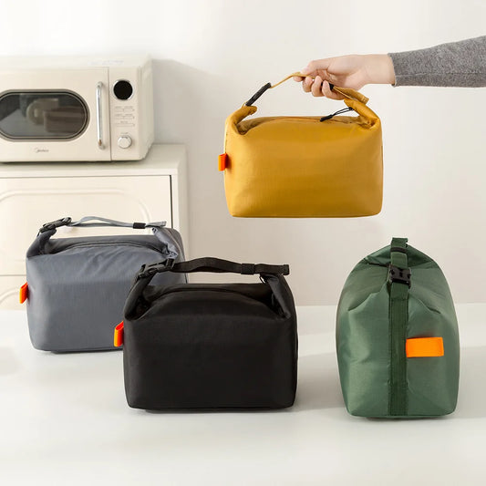 Four bags in different colors (yellow, gray, black, green) on a white surface with a microwave in the background.