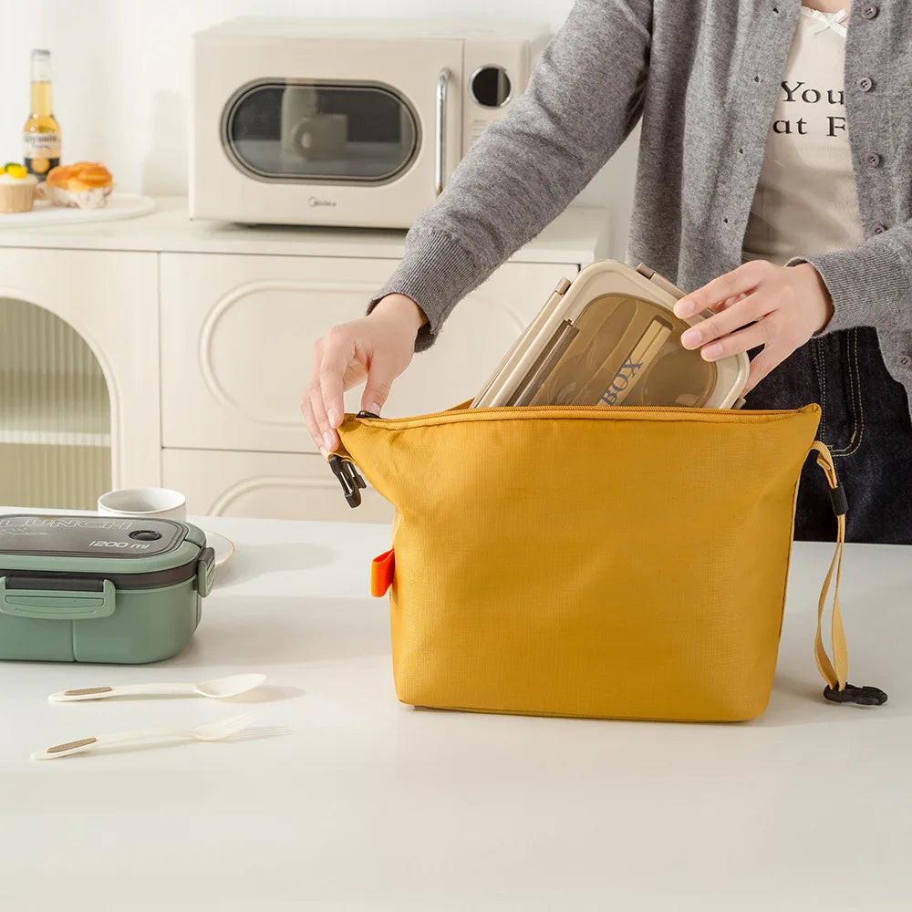 Person opening a yellow bag with kitchen items on a counter.